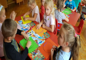 dzieci przy stoliku wypełniają narysowany kontur dużej kropki wzorami z plasteliny